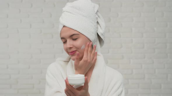 Woman in Towel Putting Cream on Face