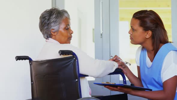 Female doctor interacting with senior woman on wheelchair