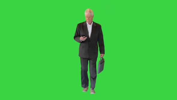 Old Businessman Walking and Texting on the Phone on a Green Screen, Chroma Key.