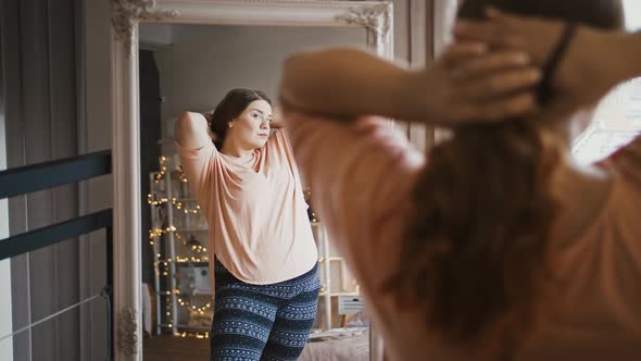 Plus Size Woman Preening Herself Making Ponytail in Front of Mirror at Home