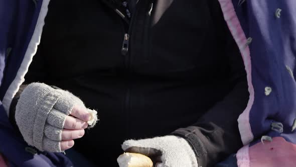 Homeless man picking apart bread and eating it