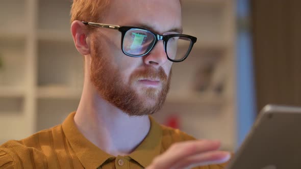 Close Up of Serious Redhead Man Using Digital Tablet 