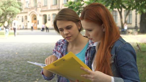 Female Students Look at Some Journal on Campus