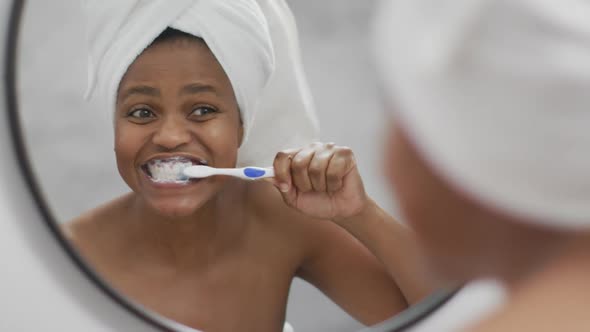 Happy african american woman brushing teeth in bathroom