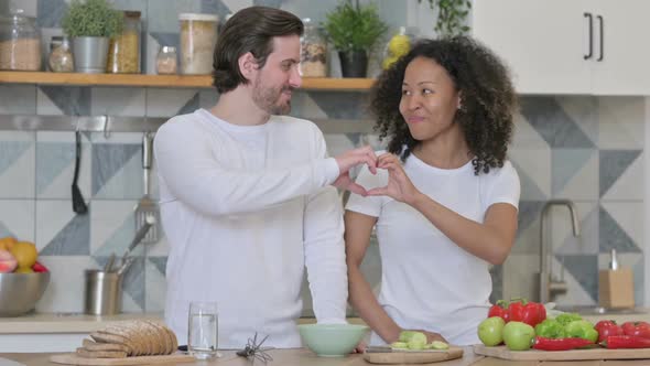 Mixed Race Couple Making Heart Shape By Hands While in Kitchen