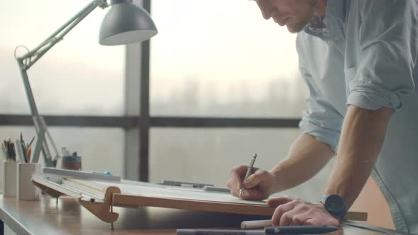 Engineer Draws Buildings on the Table Using a Pencil and Ruler