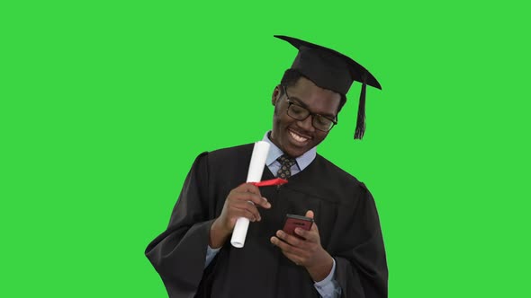 Smiling African American Male Student Graduation Robe Diploma Texting Phone Green Screen Chroma Key