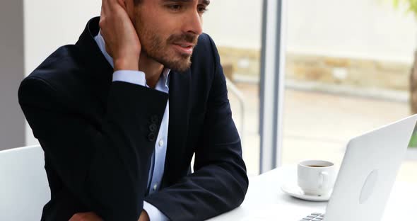 Thoughtful businessman working on laptop at desk 4k