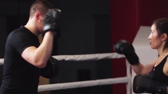 Young Woman with Long Hair Training Boxing with Her Personal Male Trainer on the Ring Hitting and