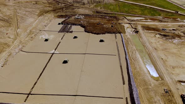 Heavy equipment preparing foundation for a landfill, aerial drone view