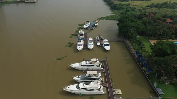 Fly in towards river marina with luxury power boats.