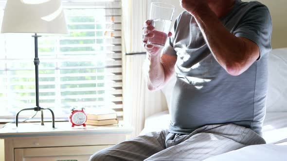 Senior man taking medicine in the bedroom