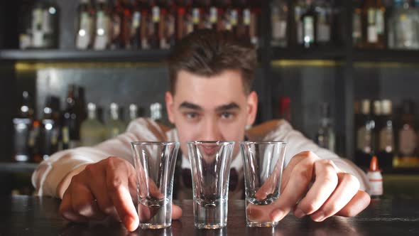 Smiling Happy Bartender Puts the Shot Glass for Vodka