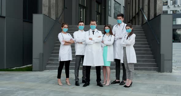 Confident Team of Doctors in Face Masks Standing With Their Arms Folded and Looking at Camera