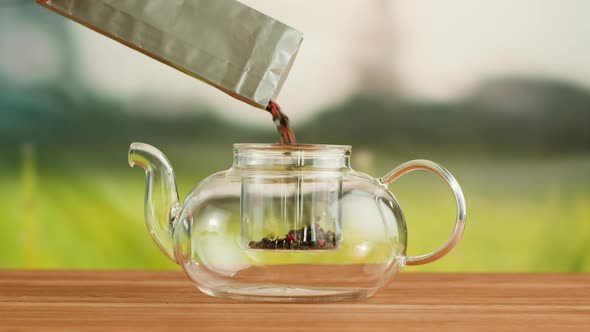 Putting Dry Tea Leaves Into Teapot on a Wooden Table