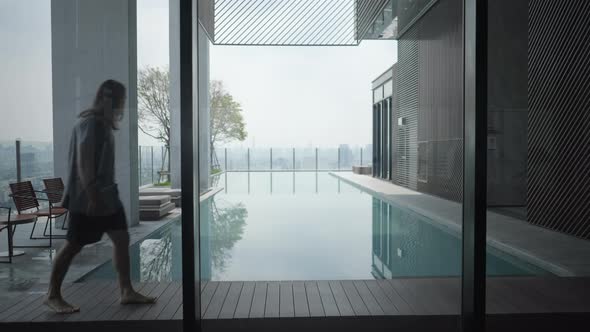 Lone Guy Is Walking By The Poolside Holding A Laptop At The Rooftop Building