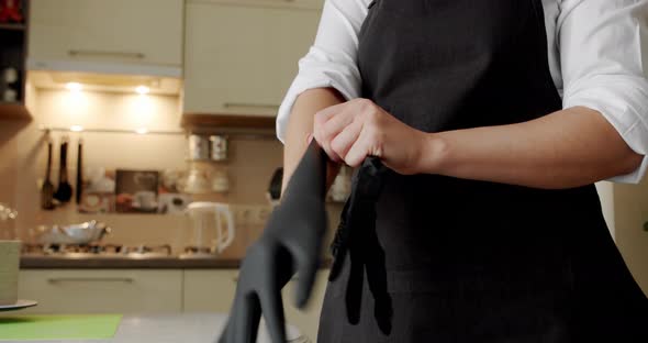 the Cook in the Kitchen Uses Black Gloves. Close Up