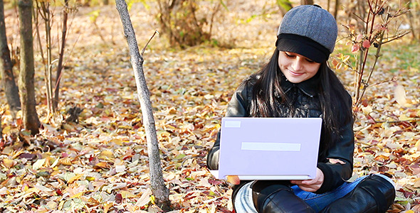 Teenager Sitting On Leaves With Laptop