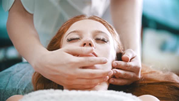 Massage - Masseuse Kneading the Chin Area To a Young Woman Using Her Palms