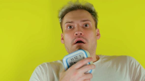 Close Up of Sleepy Man with Alarm Clock on Yellow Background