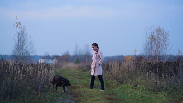 girl walking with her dog on a country road on an autumn evening