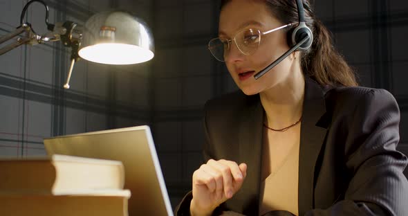 Closeup View of a Serious Woman with Headset During an Online Video Call in Front of Laptop Monitor