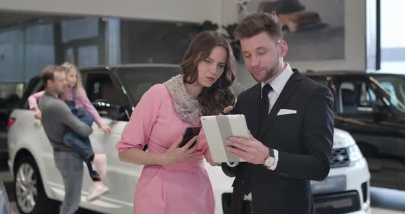 Confident Beautiful Caucasian Businesswoman Talking with Car Dealer As Her Husband and Daughter