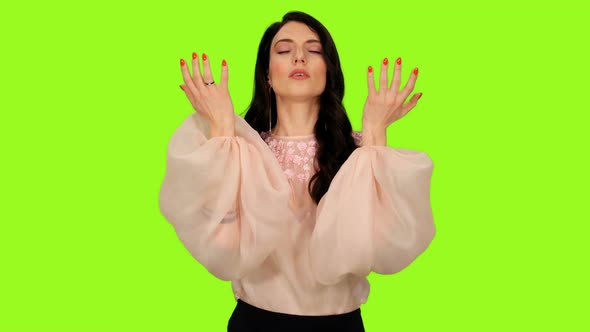 Young Brunette Female Dancing While Singing Song on Green Background