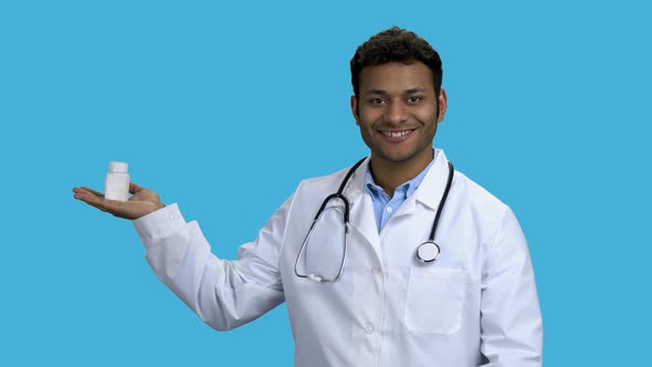 Man Doctor Showing Pills on Color Background