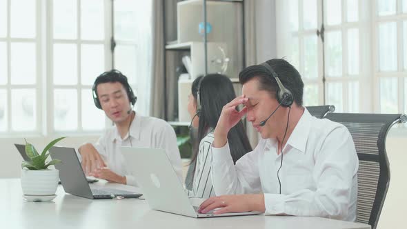 A Man Of Three Asian Call Centre Agents Headache Because His Colleagues Are Talking During Working
