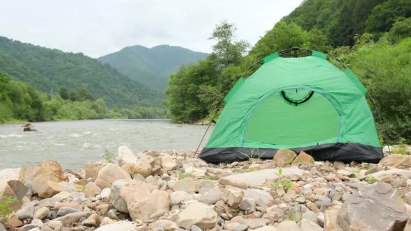 Green Tent on a Background of a Beautiful Mountain River