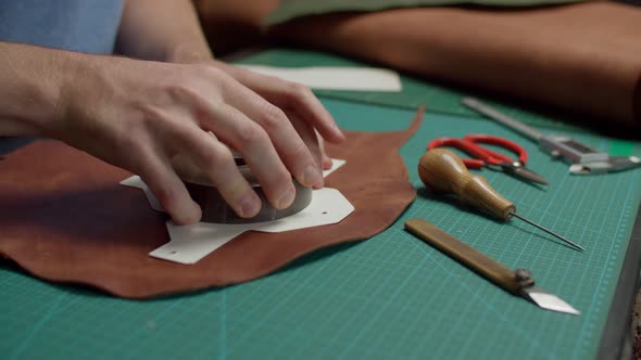 Worker Using Awl Marking Outline of Leather Detail on Scale Mat Indoor