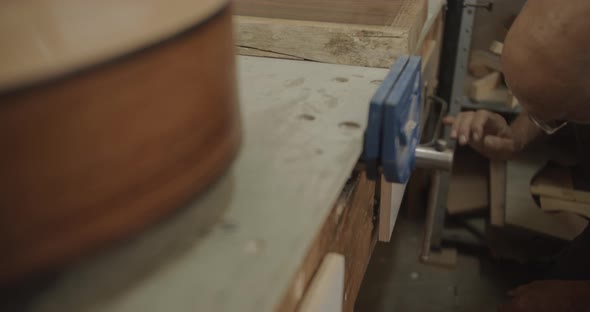 Carpenter leans down to grab a block of wood