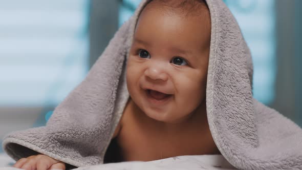 Adorable Dark Skin Baby Covered with Towel Having Fun Tummy Time