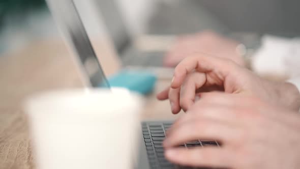 Business Man Two People Coworking in Cafe, Typing on Laptop Keyboard. Cup with Coffee on Table