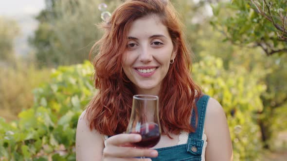 Happy Girl with Glass of Red Wine in the Vineyard