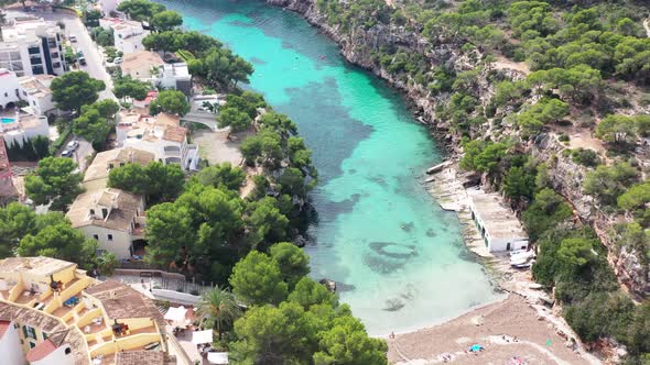 Cala Pi Beach in Mallorca Spain with swimmers and cliff beach homes, Aerial pan left shot