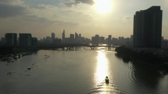 tracking a traditional river boat along the Saigon river, Vietnam  from drone with view to modern ci