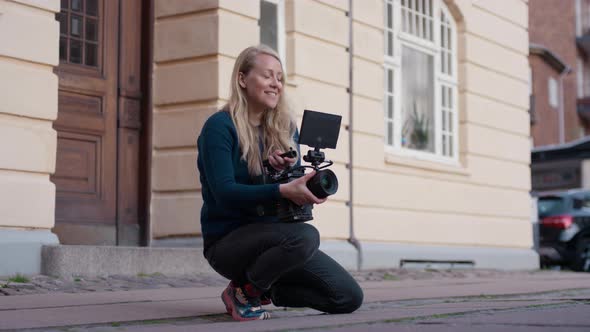 Female Film Maker Kneeling And Using Film Camera
