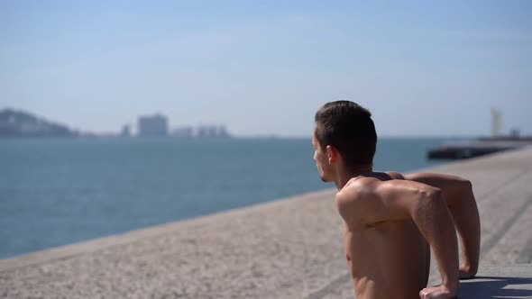 Muscular Shirtless Man in Shorts Exercising at Riverside