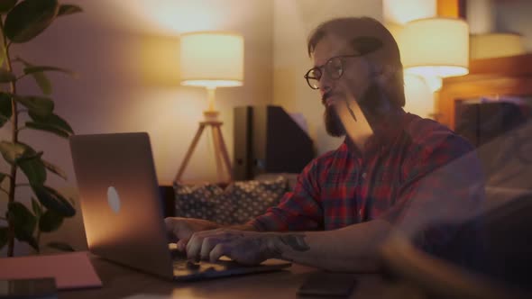 Portrait Of a Man Is Working On Laptop Computer With Glasses At Night. Businessman Working Late At