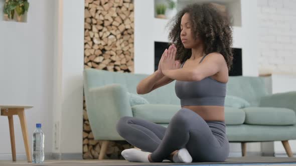 Young African Woman Doing Meditation on Yoga Mat at Home