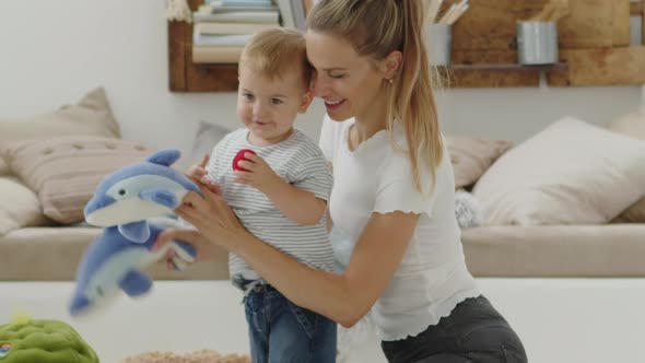 Happy and smiling mom with baby playing in living room at home