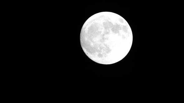 Glowing Huge Full Moon As Seen From Earth Through the Clouds Against Starry Night Sky