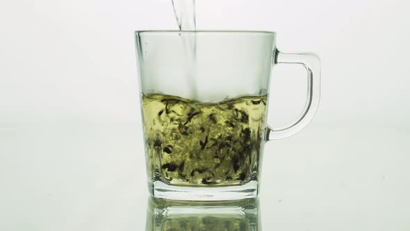 Black Tea Particles Pouring Into Glass Transparent Mug and Filled with Boiling Water To Brew Tea