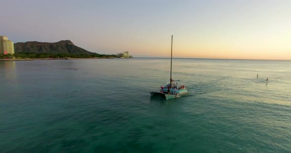 Aerial drone shot circles a small sailboat revealing a sunset on the horizon ALTERNATIVE VERSION