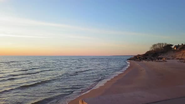 Aerial view of Baltic sea coast on a sunny evening, golden hour, steep seashore dunes damaged by wav