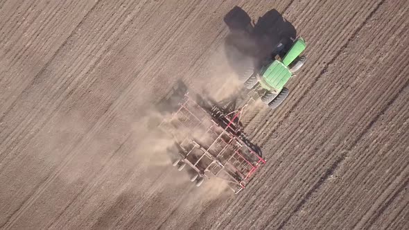 Top Down Aerial View of Green Tractor Cultivating Ground and Seeding a Dry Field