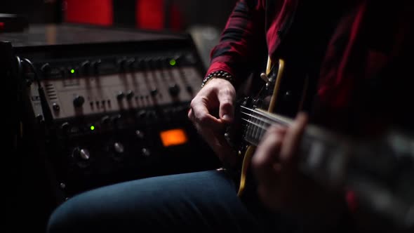 Closeup of Musician Playing Solo Guitar Part on Electric Guitar While Sitting at Music Studio