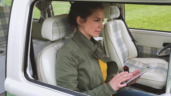 Woman sitting in camper and using tablet